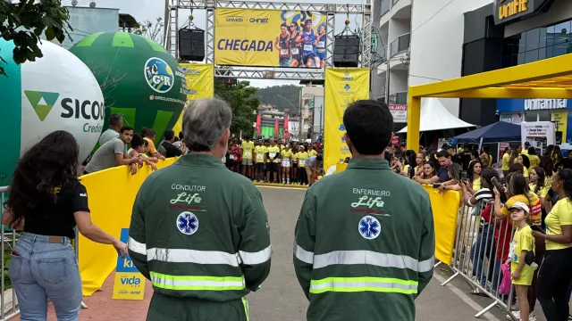 Condutor e enfermeiro da Life Remocenter de costas, observando a linha de chegada de uma corrida de rua cercada de público