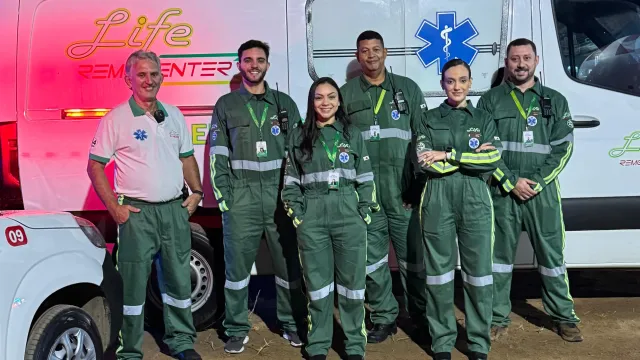 Equipe médica da Life Remocenter uniformizada ao lado de ambulância UTI móvel durante atendimento noturno
