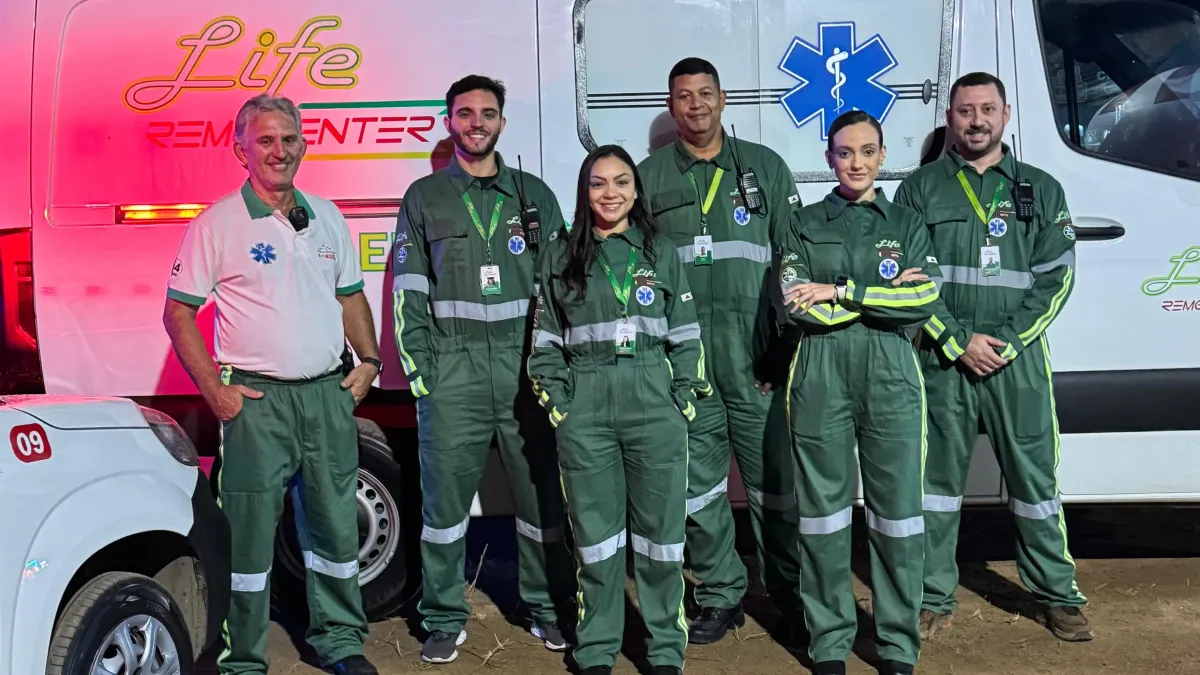 Equipe médica da Life Remocenter uniformizada ao lado de ambulância UTI móvel durante atendimento noturno